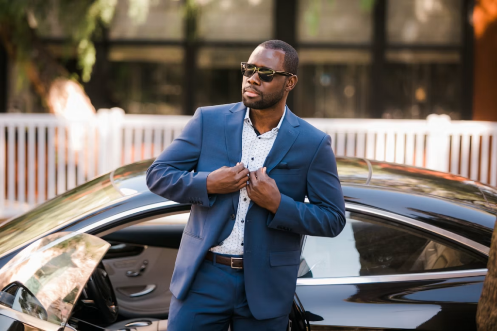 homme en costume bleu debout à côté d'une voiture noire