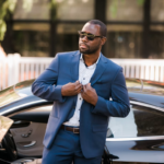 homme en costume bleu debout à côté d'une voiture noire